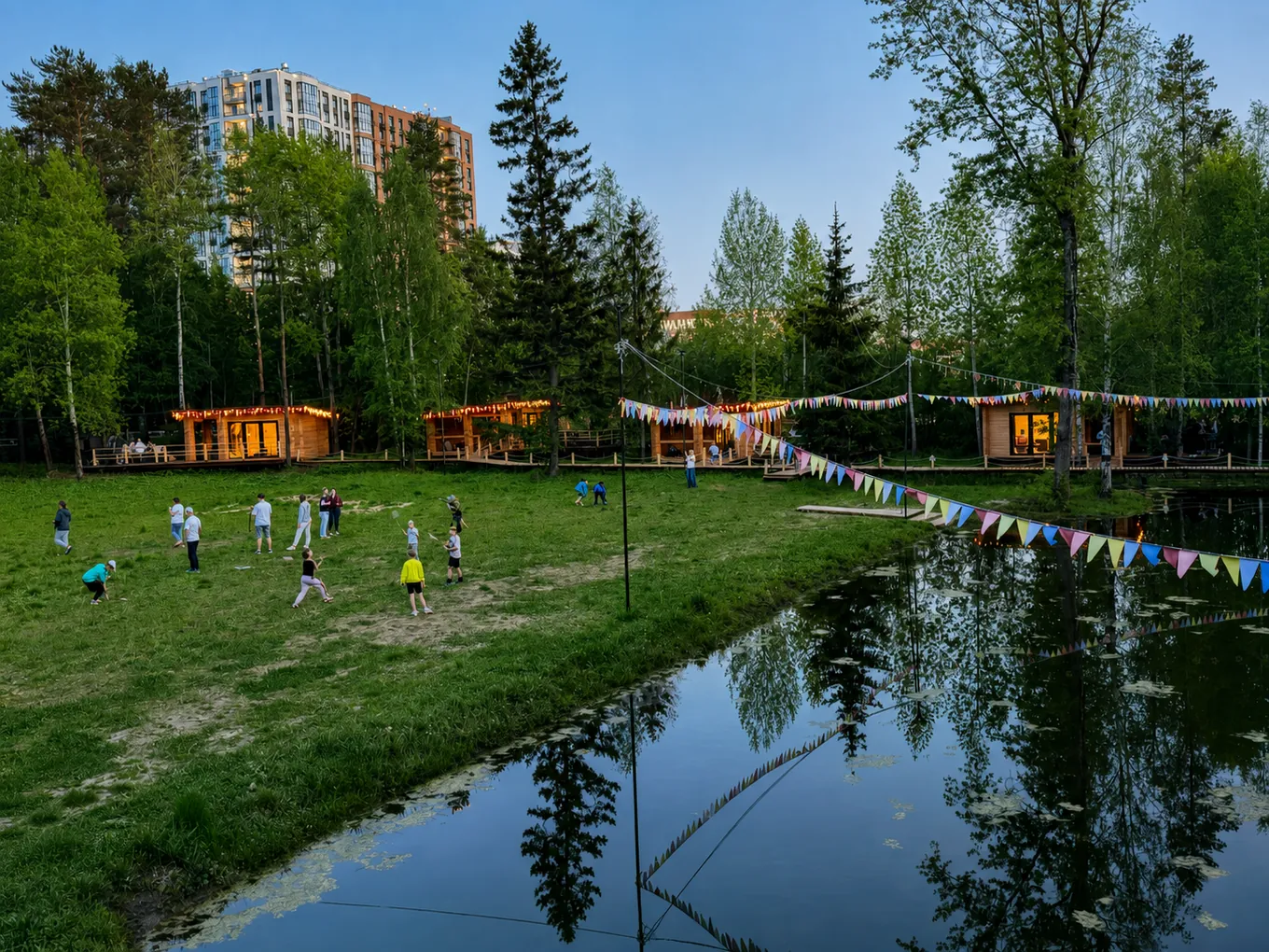 Гости на поляне у пруда, за лесом видны дома города